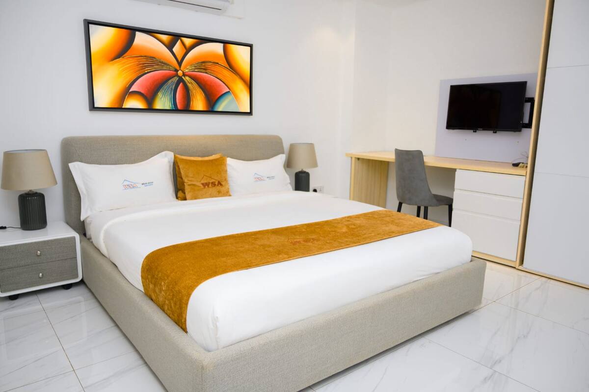 Ein modernes Hotelzimmer mit einem großen Bett, einem Schreibtisch, einem Fernseher und einem Bild an der Wand.