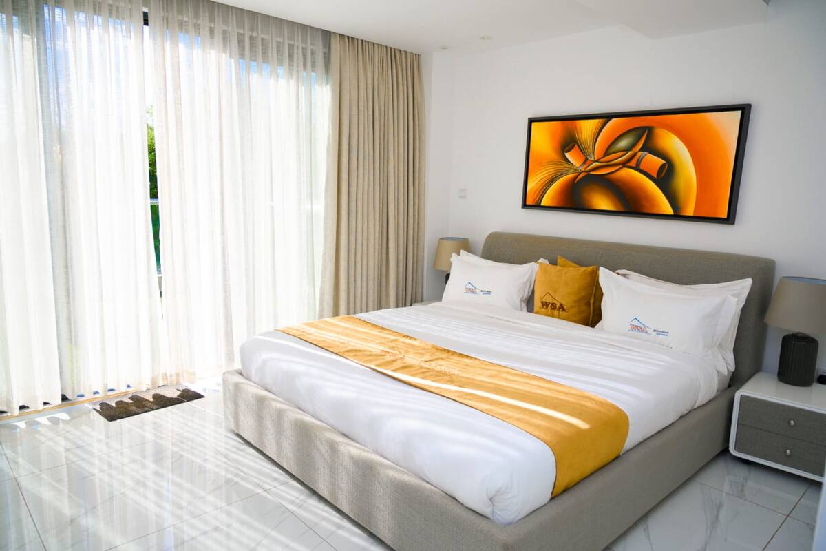 Ein Hotelzimmer mit einem großen Bett, einem Nachttisch, einer Lampe und einem Bild an der Wand.