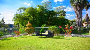 A well-maintained outdoor area with a grassy lawn, a seating area with chairs and a table, and a variety of plants and trees.