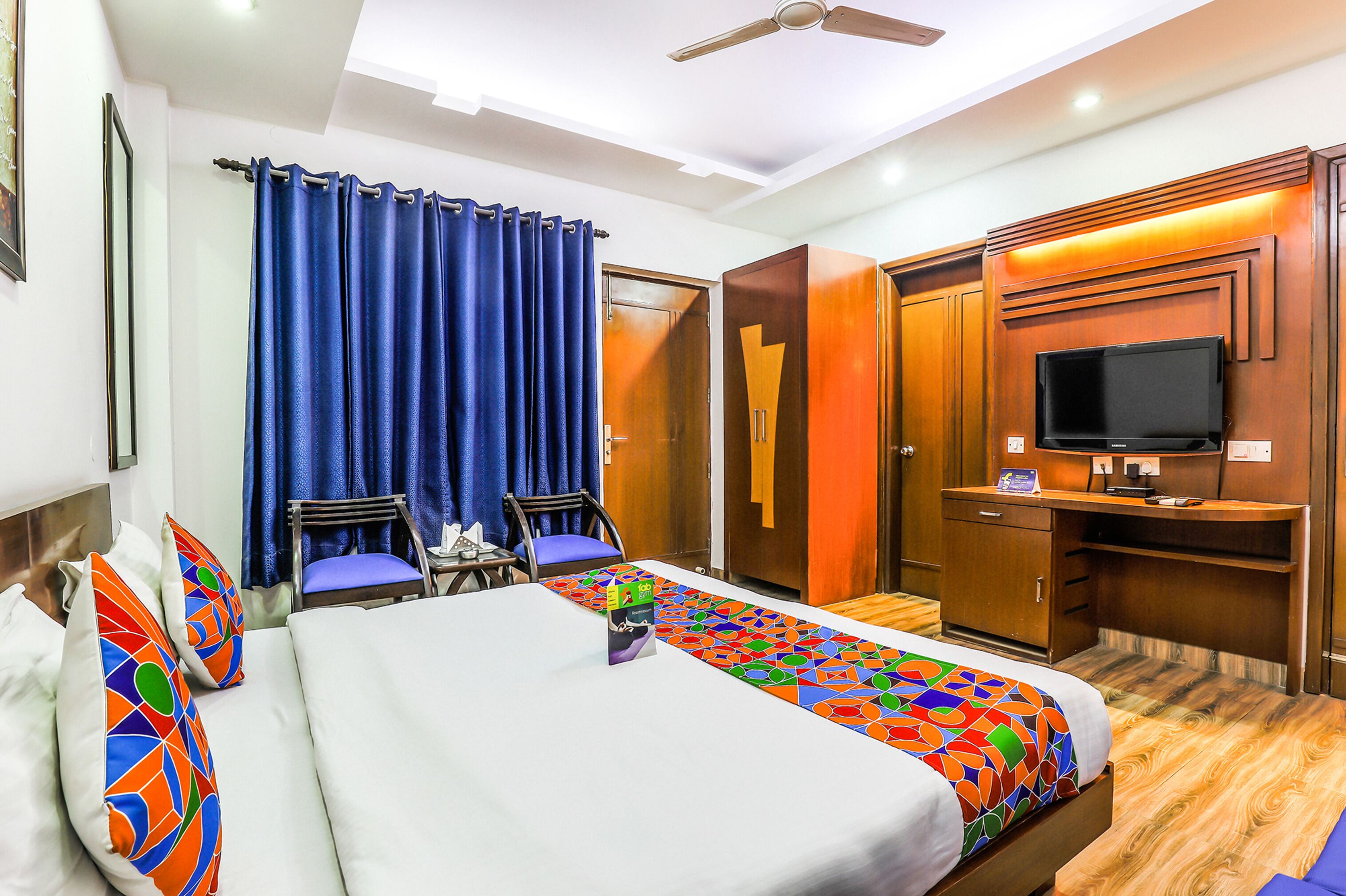 Een hotelkamer met een groot bed, een bureau met een televisie, een kledingkast en een douche.