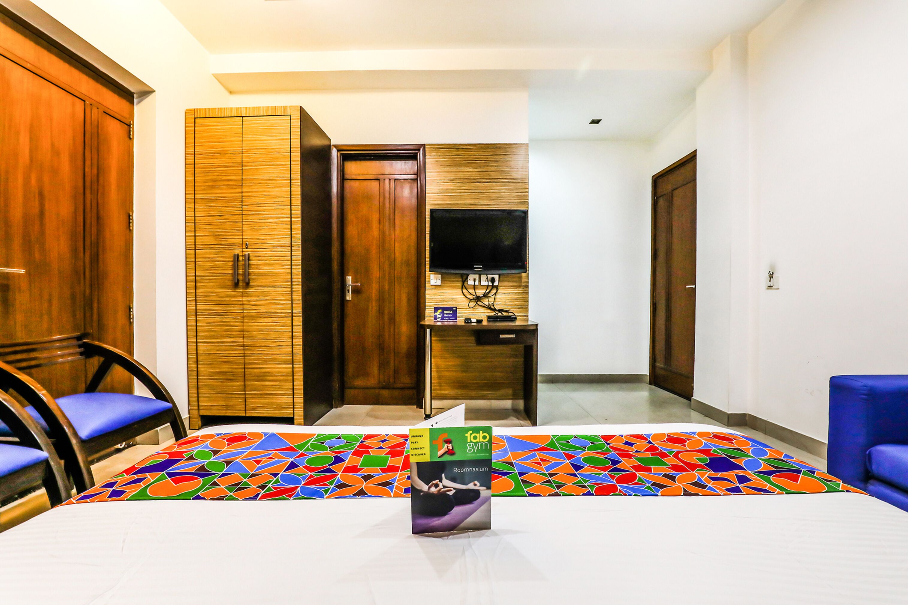 A hotel room with a bed, a desk, a television, and a wardrobe.