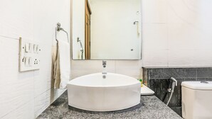 A bathroom with a round white sink, a mirror, a towel rack, and a shower area. - FabHotel The Maple Stays - Nr. Leisure Valley Park, Iffco Chowk (Gurugram)