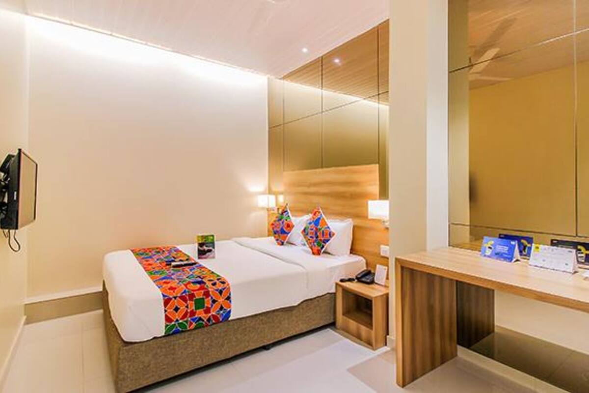 Quarto de hotel com cama, mesa de cabeceira, abajur e telefone.