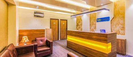 Un'area reception di un hotel con una scrivania in legno, divani in pelle e un cartello che indica 'fab hotels'.