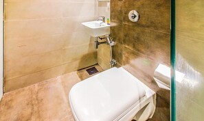 A small bathroom with a white toilet, a sink, and a shower. - Fabhotel Rk International (Mumbai)