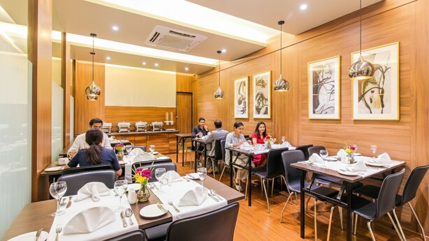 A restaurant with wooden panel walls, multiple dining tables, and framed artwork on the walls. - Fabhotel Rk International (Mumbai)