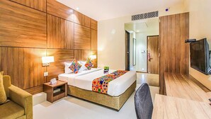 A hotel room with a large bed, wooden panel walls, a TV, and a small desk. - Fabhotel Rk International (Mumbai)