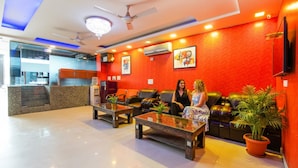 A lobby with a red wall, a ceiling fan, and a reception desk. - FabHotel TP Suites (New Delhi)