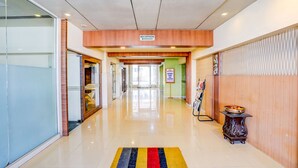 A hotel reception area with a clear sign indicating the reception desk, a glass wall on the left, and a colorful rug on the floor. - FabHotel Devanshi Inn (Panvel)