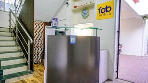 Zona de recepción con un mostrador de vidrio, un reloj y un cartel que dice 'fab hotels'.
