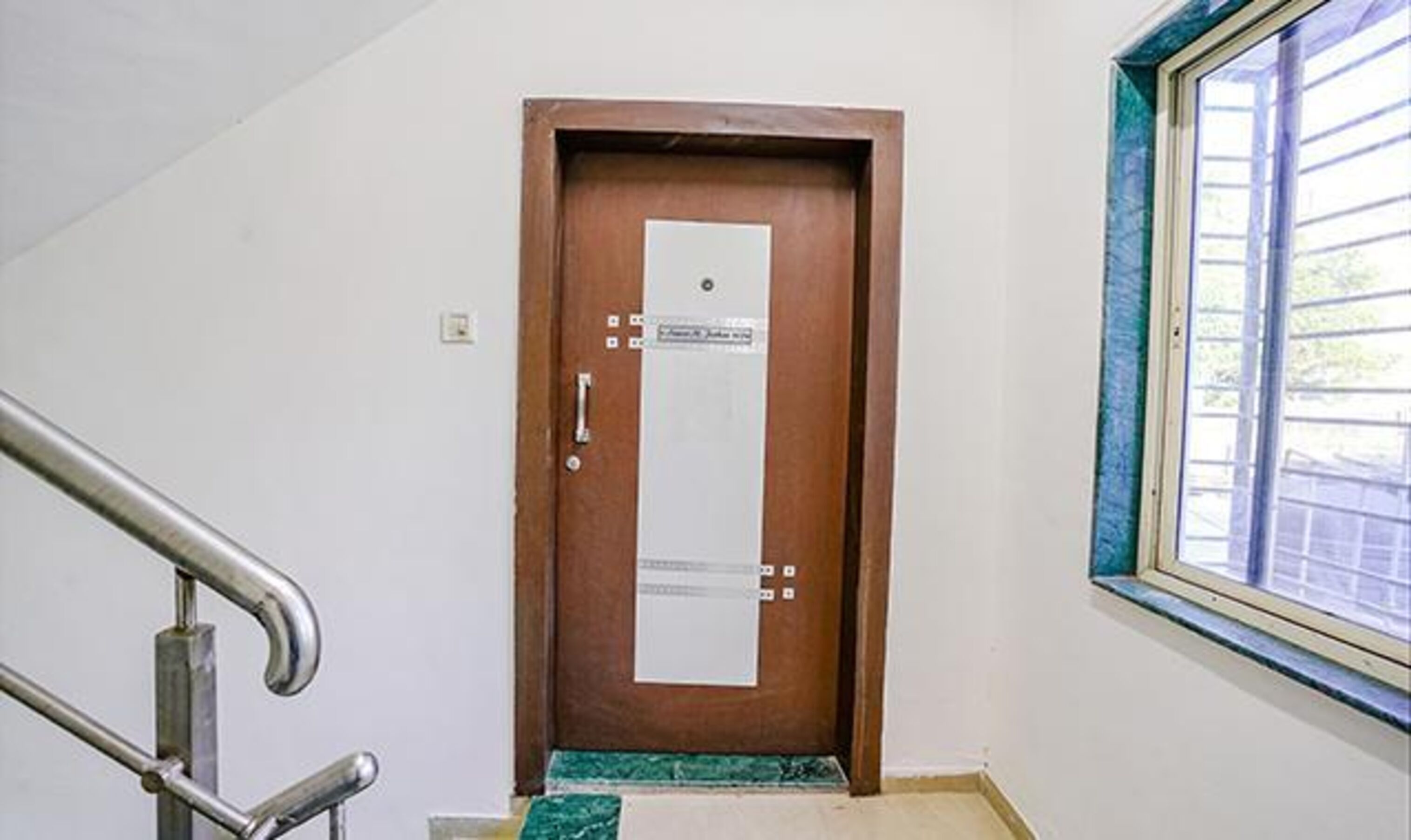 Una puerta de madera con un letrero, una barandilla de metal y una ventana que da a vistas del exterior.