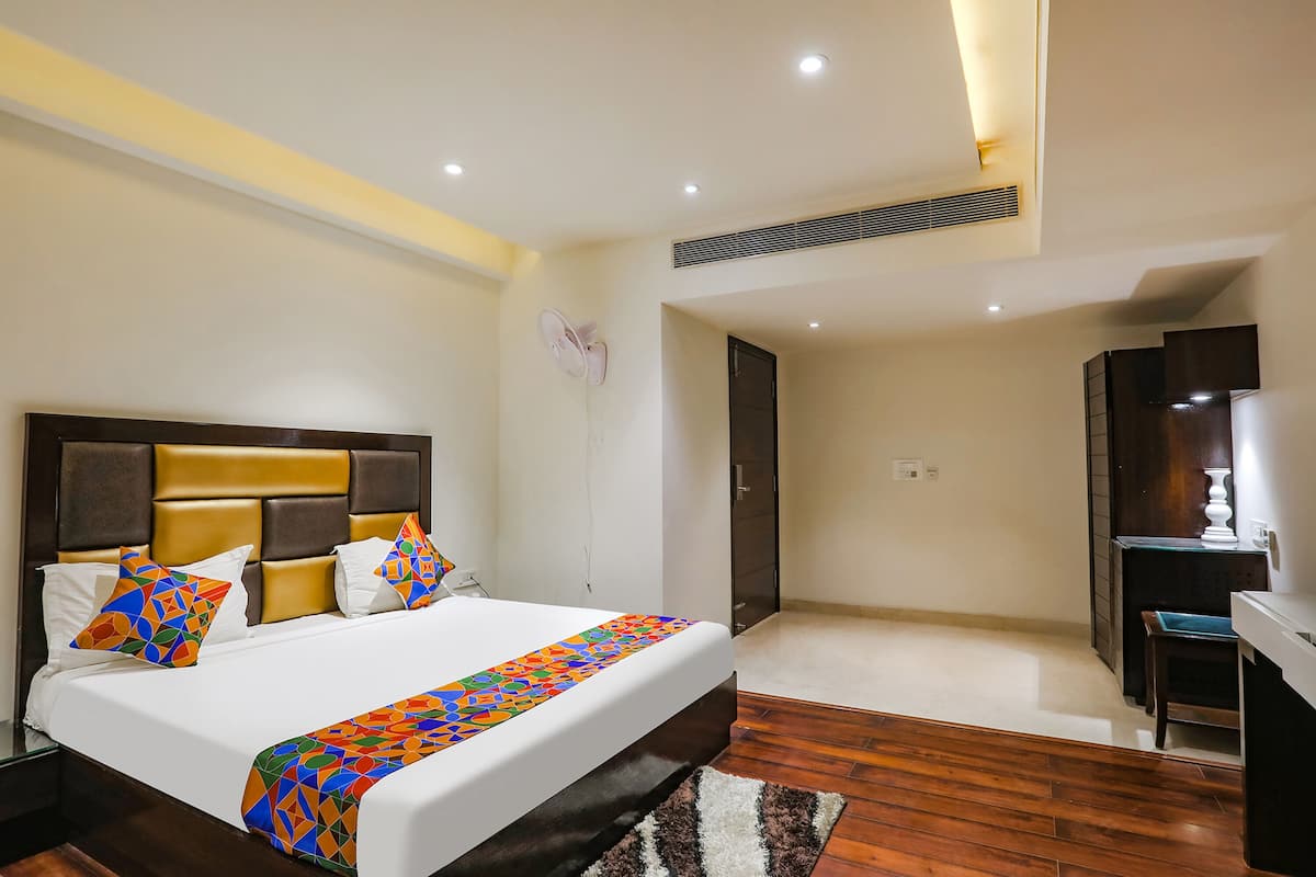 A hotel room with a large bed, a desk, and a chair.