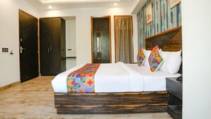 A modern hotel room with a large bed, a wooden headboard, and a colorful geometric-patterned bedspread. - FabHotel Delta Suites I (New Delhi)