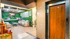 A lobby with a reception desk, seating area, and an elevator. - FabHotel Delta Suites I (New Delhi)