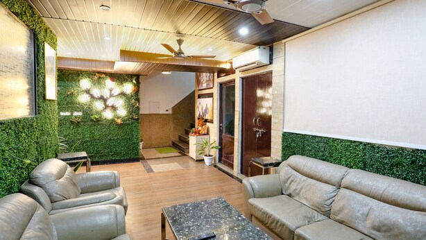 A modern lounge area with leather sofas, a coffee table, and a ceiling fan. - FabHotel Delta Suites I (New Delhi)