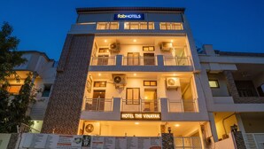 Ein mehrstöckiges Hotel mit Balkonen, Klimaanlagen und einem Schild mit der Aufschrift 'HOTEL THE VINAYAK'.