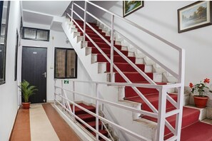 Una escalera con barandillas blancas y peldaños alfombrados de rojo, que conduce a un piso superior.