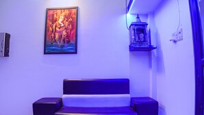Ein Raum mit einer blauen Wand, einem gerahmten Gemälde, einem kleinen Schrein und einem Sofa.