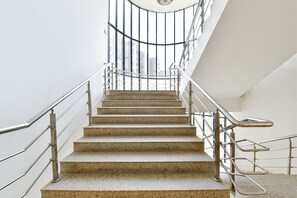 Eine Treppe aus Stein mit Metallgeländern, die zu einem geschwungenen Glasbalkon führt.