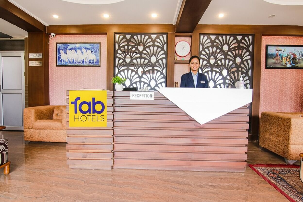 A reception desk with a 'fab hotels' sign, a receptionist, and a decorative wall with a clock and framed pictures.