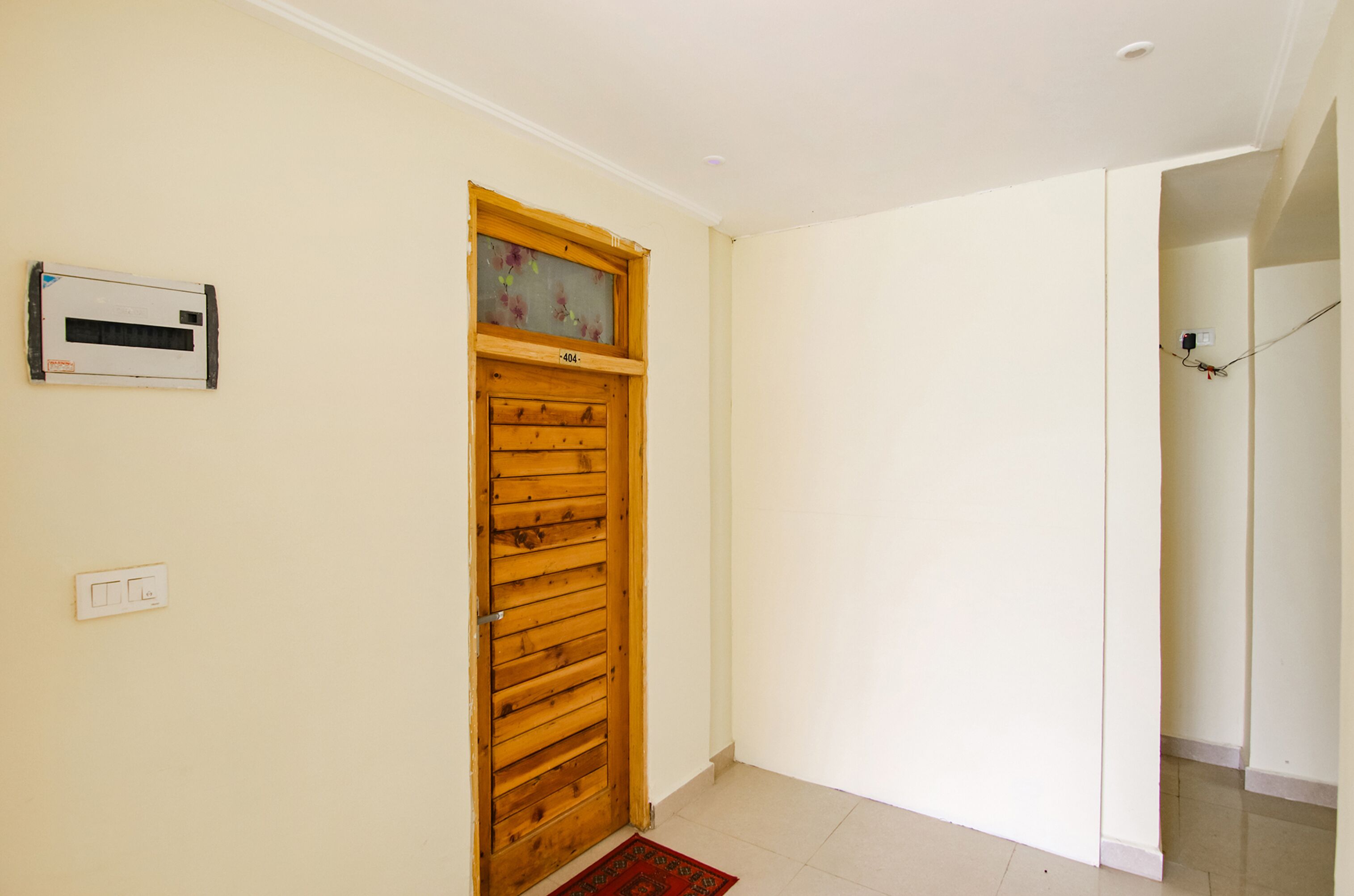 Un couloir avec une porte en bois, un climatiseur fixé au mur et une prise de courant.