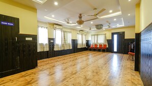 A spacious room with a wooden floor, ceiling fans, and a hand wash sign on a door. - Fabhotel Sairam Residency (Bengaluru)