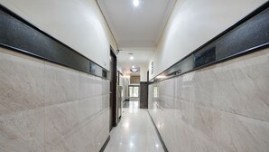 A corridor with marble walls and a shiny tiled floor, leading to a door at the end. - Fabhotel Sairam Residency (Bengaluru)