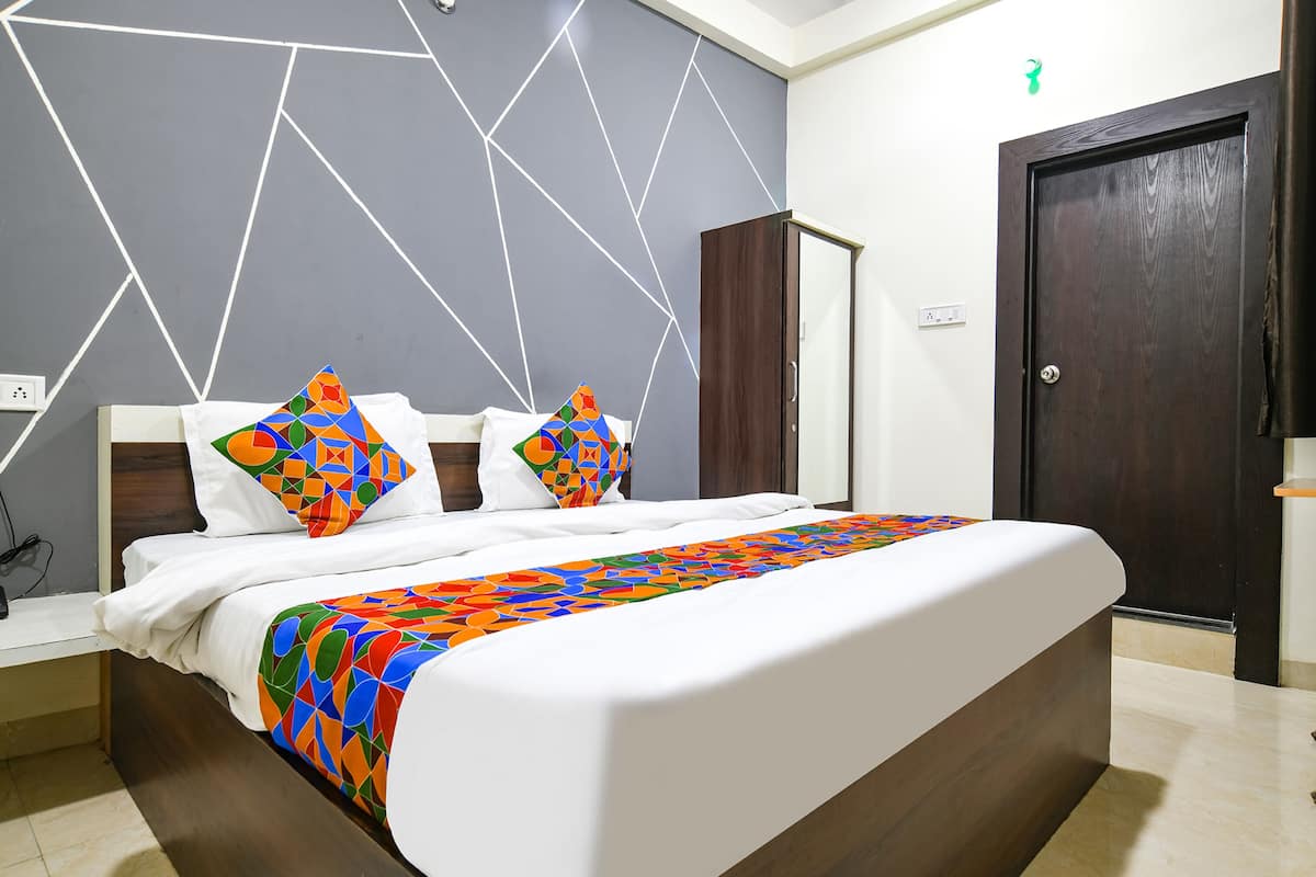 A modern bedroom with a large bed, geometric wall design, and a dark wooden wardrobe.