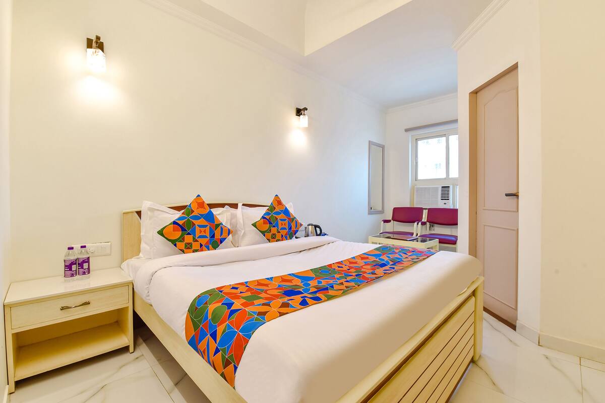 A neatly arranged hotel room with a bed, bedside table, and a window.