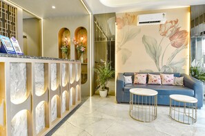 A reception area with a marble reception desk, a blue sofa, and two round tables. - Fabhotel The Tulip Regency (Jaipur)