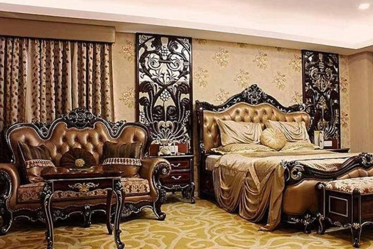 A luxurious bedroom with a large bed, ornate headboard, and a classic sofa.