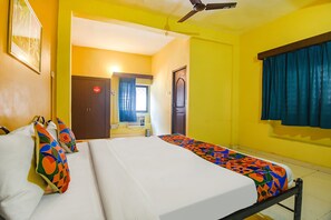 A hotel room with a bed, a ceiling fan, a window with curtains, and a door. - FabExpress Casa Paradiso (Panaji)