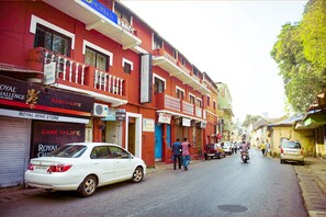 A street with buildings, a white car parked on the side, and a motorbike in the distance. - FabExpress Casa Paradiso (Panaji)