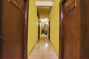 A hotel hallway with wooden doors and yellow walls. - FabExpress Casa Paradiso (Panaji)