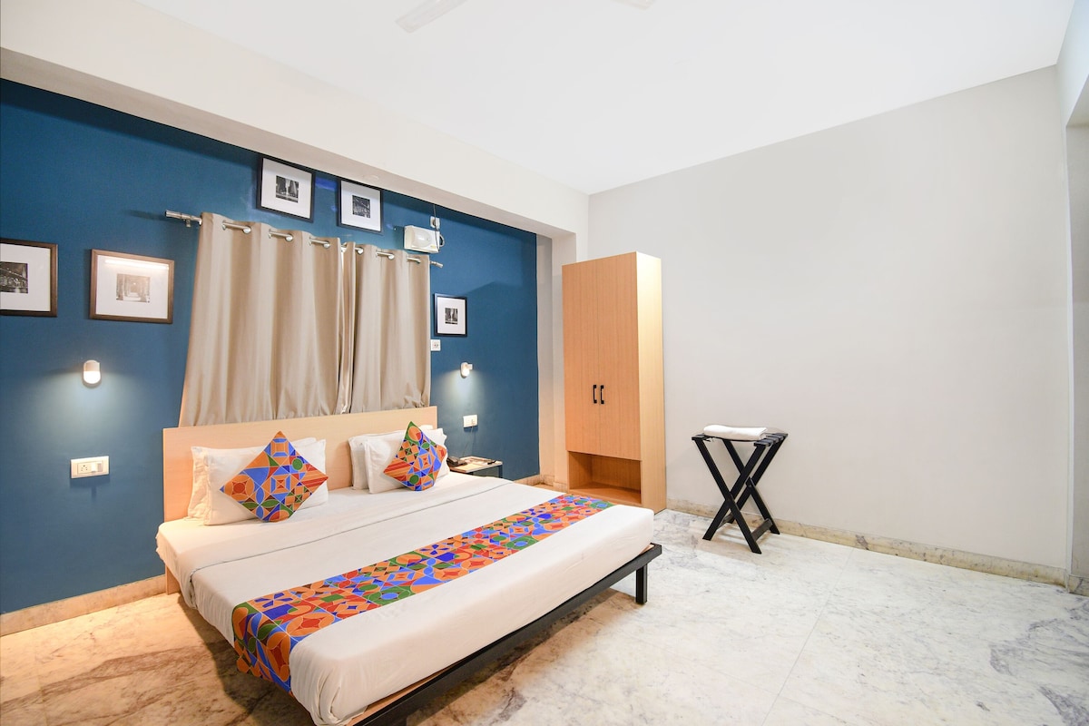 A bedroom with a bed, a wooden wardrobe, a small table, and a blue accent wall.