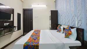 Ein Hotelzimmer mit Bett, Fernseher, Kleiderschrank und Tür.