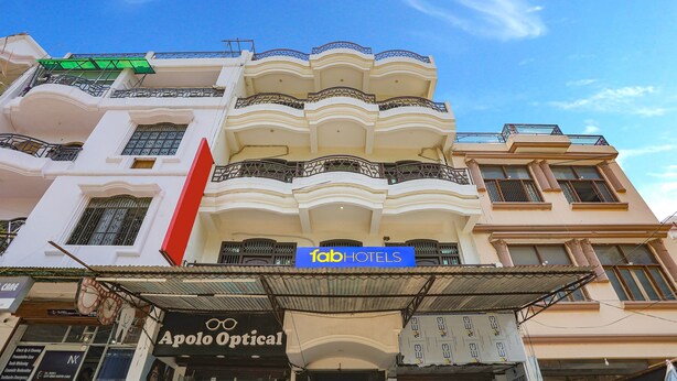 Ein Hotel mit Balkonen, ein Schild für 'fabHOTELS' und ein Schaufenster mit der Aufschrift 'Apollo Optical'.