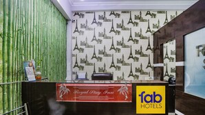 Ein Empfangsschalter mit einem Schild 'Royal Play Inn', einer Bambuswand und dem Logo 'fab hotels'.