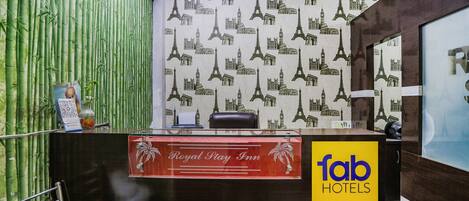 Una recepción con un cartel que dice 'Royal Play Inn', pared de bambú y el logotipo de 'fab hotels'.