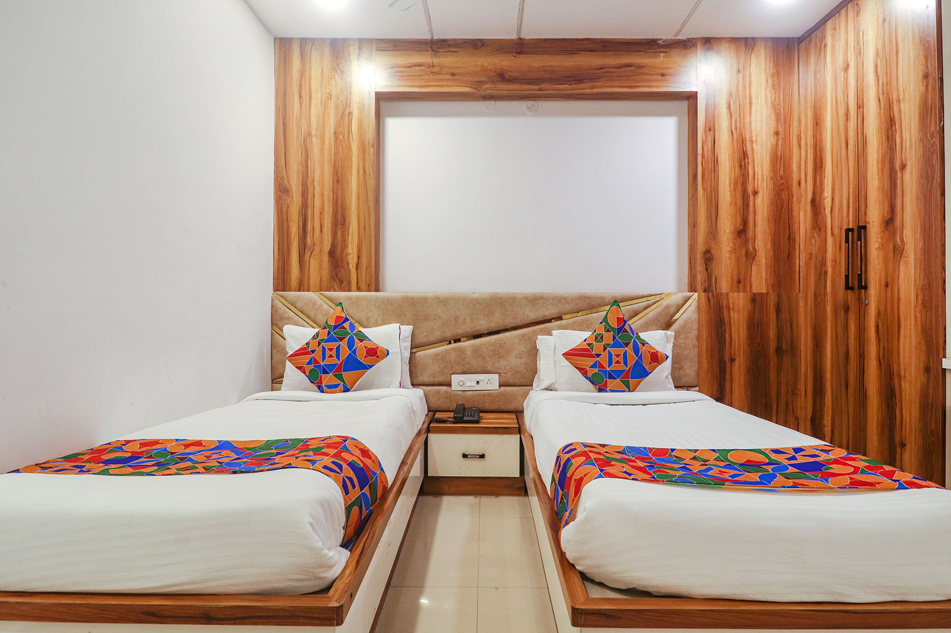 A double room with two beds, a wooden headboard, and a small bedside table with a phone.