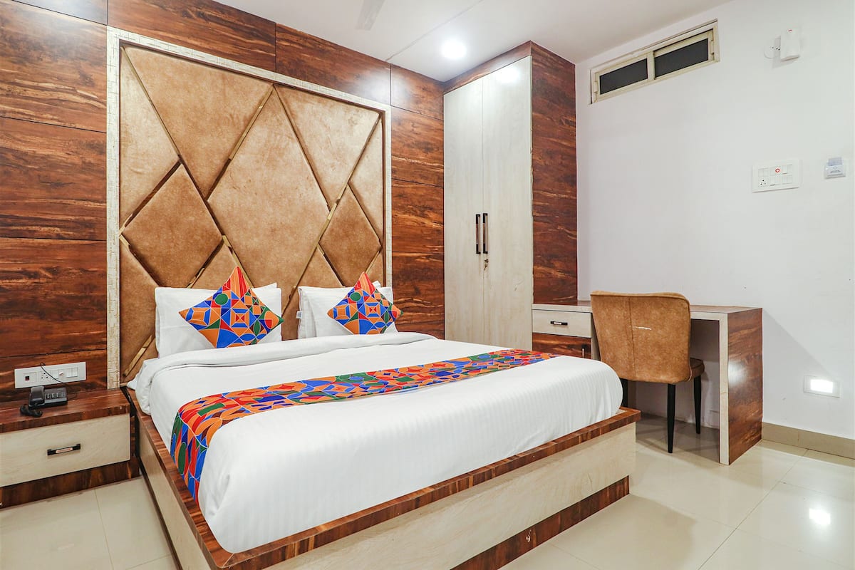 A bedroom with a large bed, a desk, and a wardrobe.