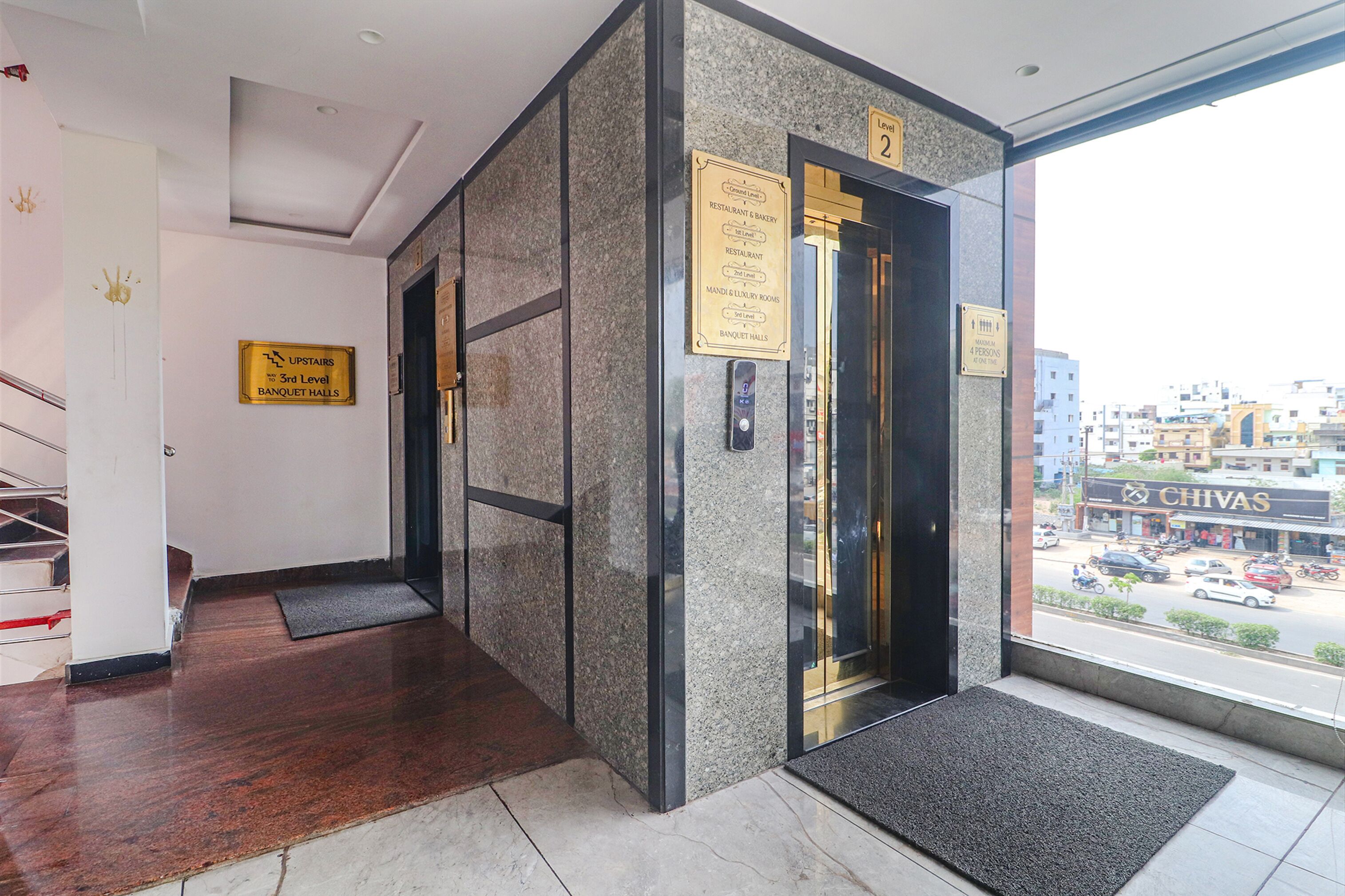 A hotel entrance with a marble floor, a staircase, and a view of the street outside.