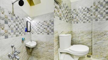 Un baño con lavabo, inodoro y ducha. Las paredes están cubiertas de azulejos con un diseño decorativo.