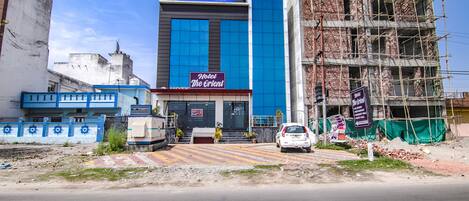 A hotel named 'Hotel The Orient' with a modern facade, a blue and white color scheme, and a signboard advertising 'Tab Hotels'.
