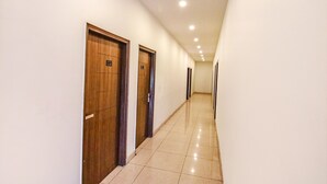 A long, narrow hallway with wooden doors and a tiled floor. - Fabhotel The Orient (Haridwar)