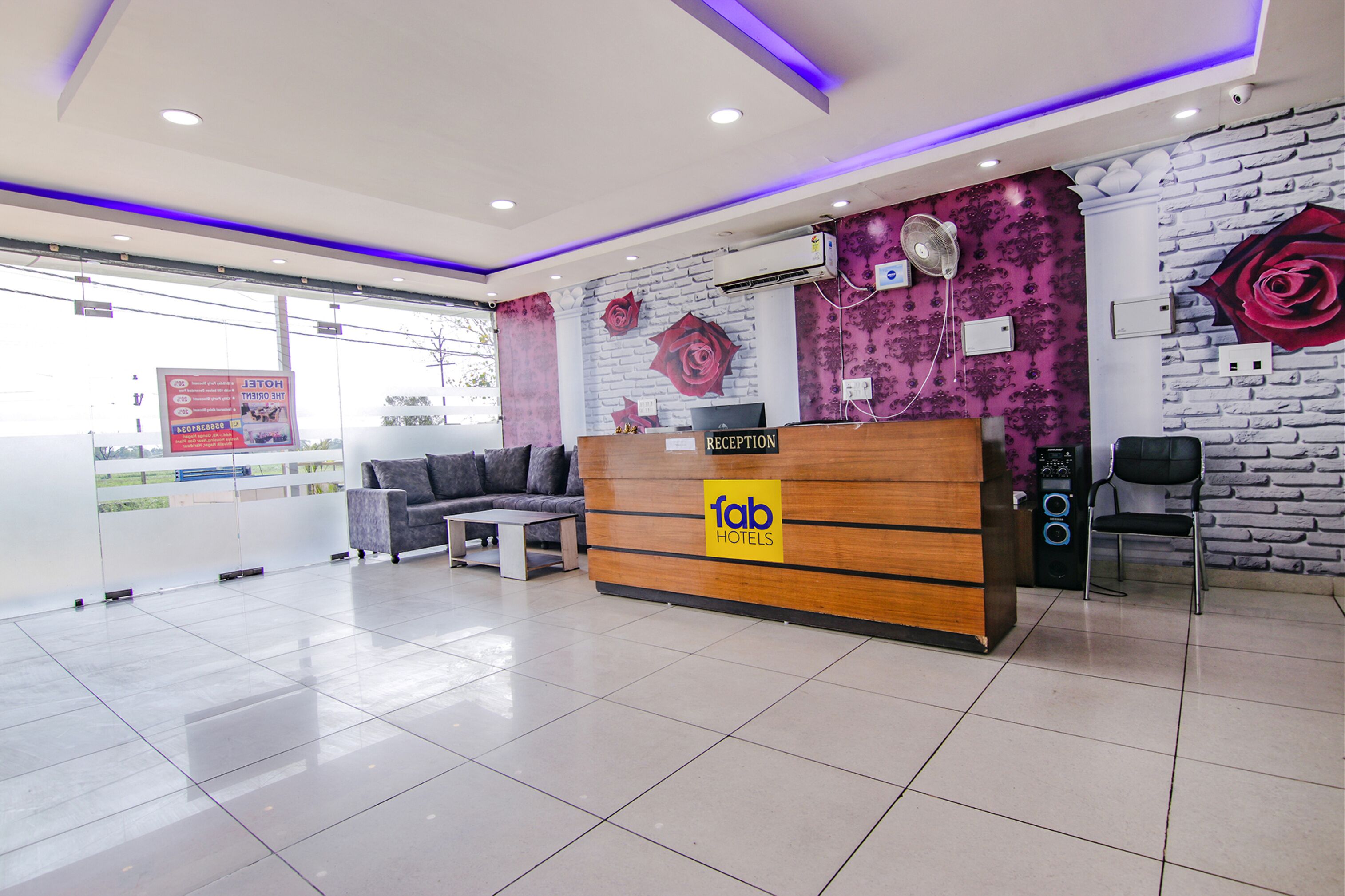 A hotel reception area with a reception desk, a sofa, and a fan.