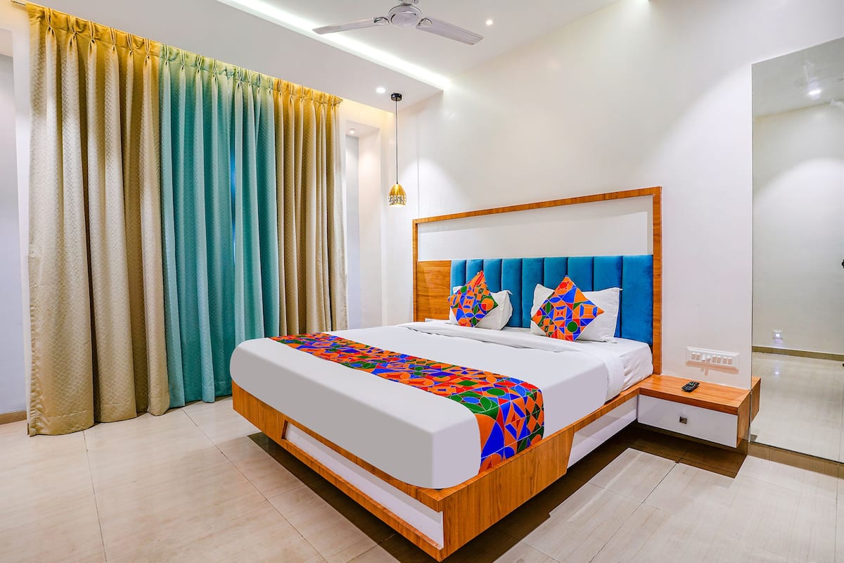 A modern hotel room with a large bed, wooden headboard, and a bedside table with a remote control.