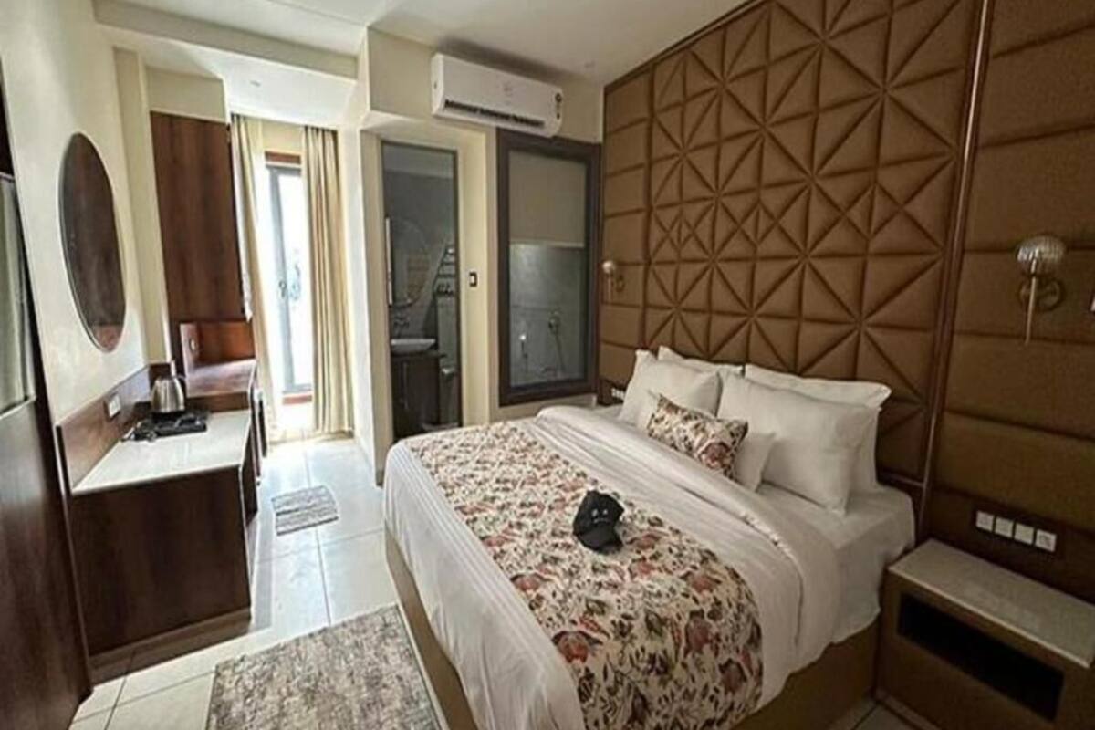 A hotel room with a bed, a desk, a mirror, and a wardrobe.