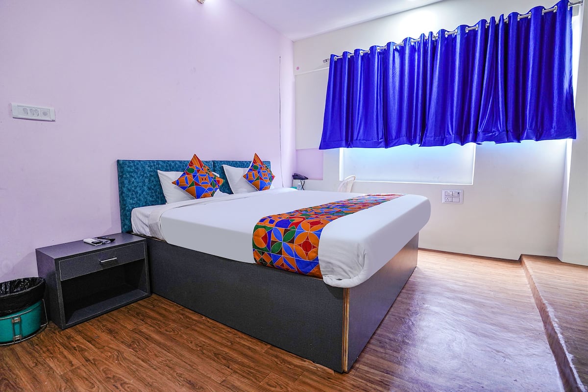 A modern bedroom with a bed, nightstand, and a window with blue curtains.