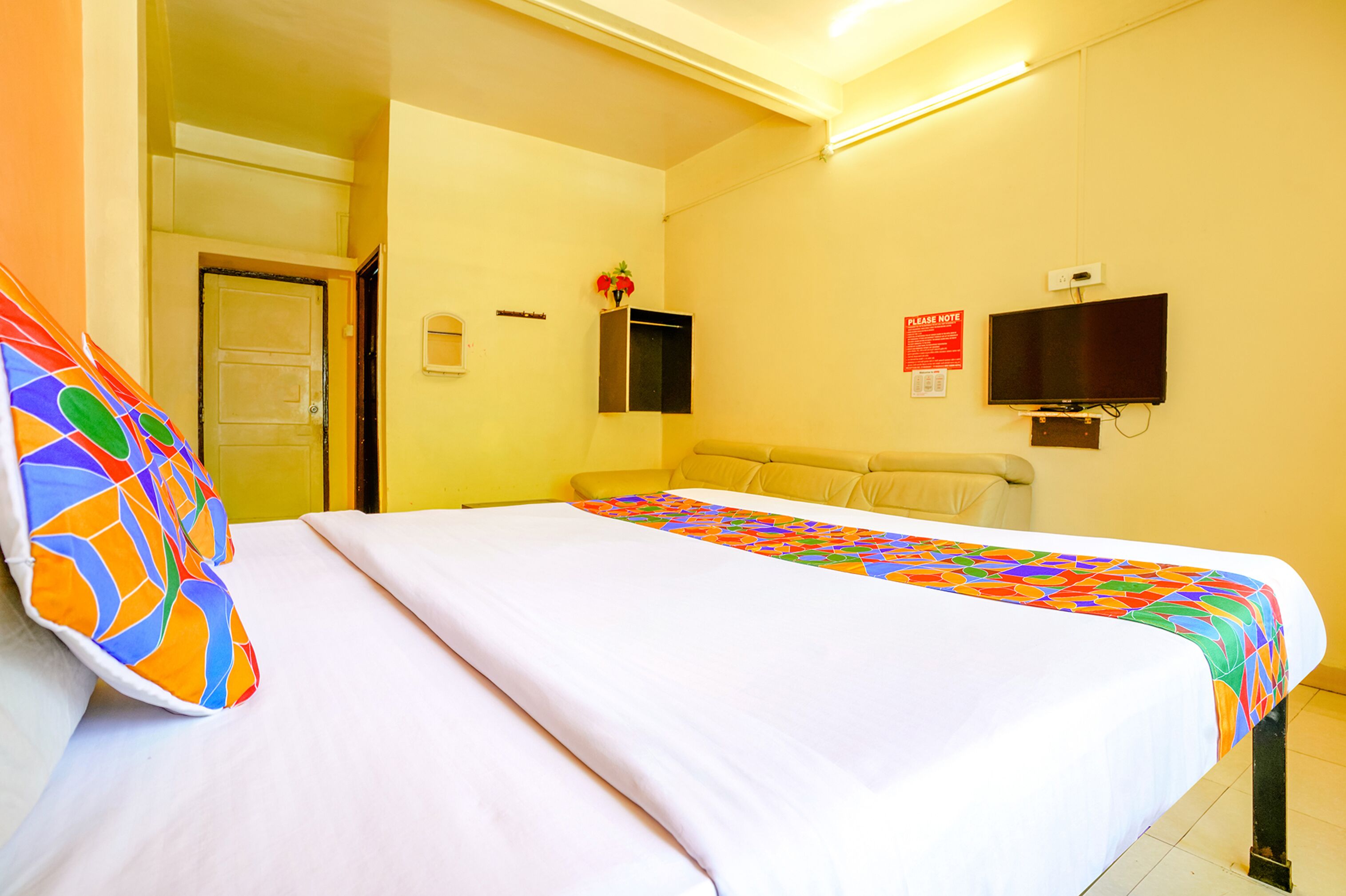 A hotel room with a bed, a television, and a sign on the wall.
